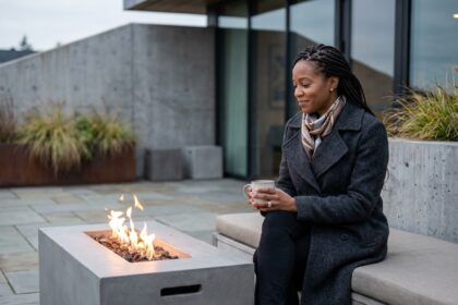 Femme élégante en manteau wool et foulard près d'un feu de cheminée