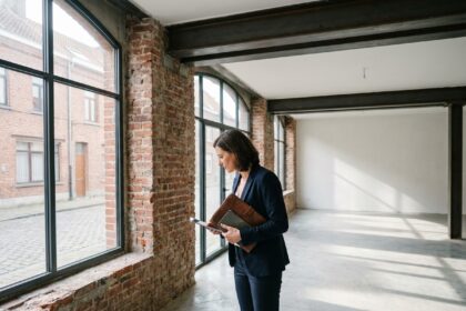 Professionnelle visitant un local d'activité vide à Lille avec murs en briques apparentes et sol béton